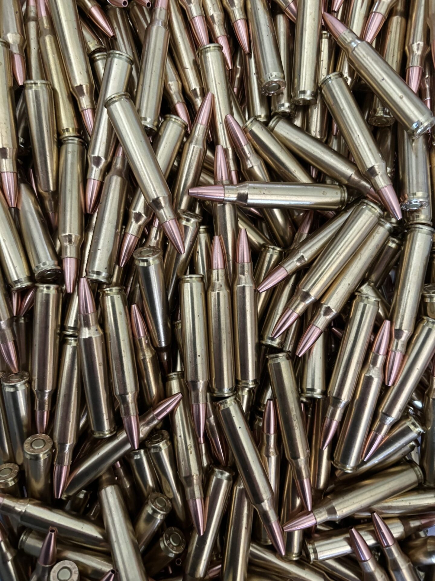 ms Ammunition – High-Quality Ammunition for Rifles and Shotguns" A collection of shiny brass bullet casings with copper-tipped projectiles, including rifle cartridges and shotgun shells, tightly packed together. This assortment showcases high-quality ammo designed for various firearm needs. The image highlights the availability of bulk ammunition options, perfect for ensuring a steady supply of ammunition. Bulk Ammo Available for Purchase"