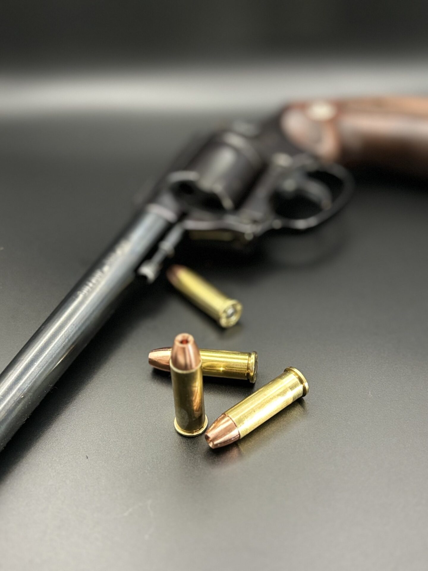 ms Ammunition – High-Quality Ammunition for Rifles and Shotguns" A close-up image of a revolver resting on a dark surface, surrounded by various high-quality ammo. The revolver features a wooden grip, while the rifle cartridges and ammunition with brass casings and pointed tips are scattered around it. The background is blurred to emphasize the firearm and its accompanying bulk ammunition, including shotgun shells. Bulk Ammo Available for Purchase"